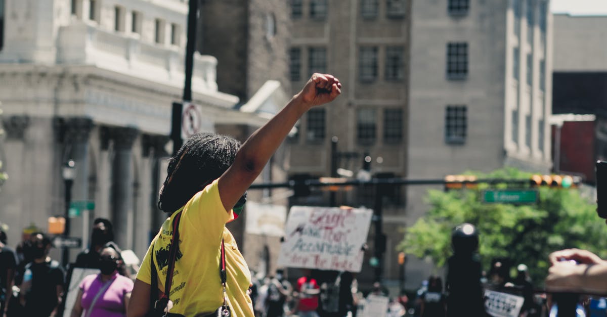 Why did Black Panther change his mind? - African American female raising fist while standing in demonstration against police brutality in daylight