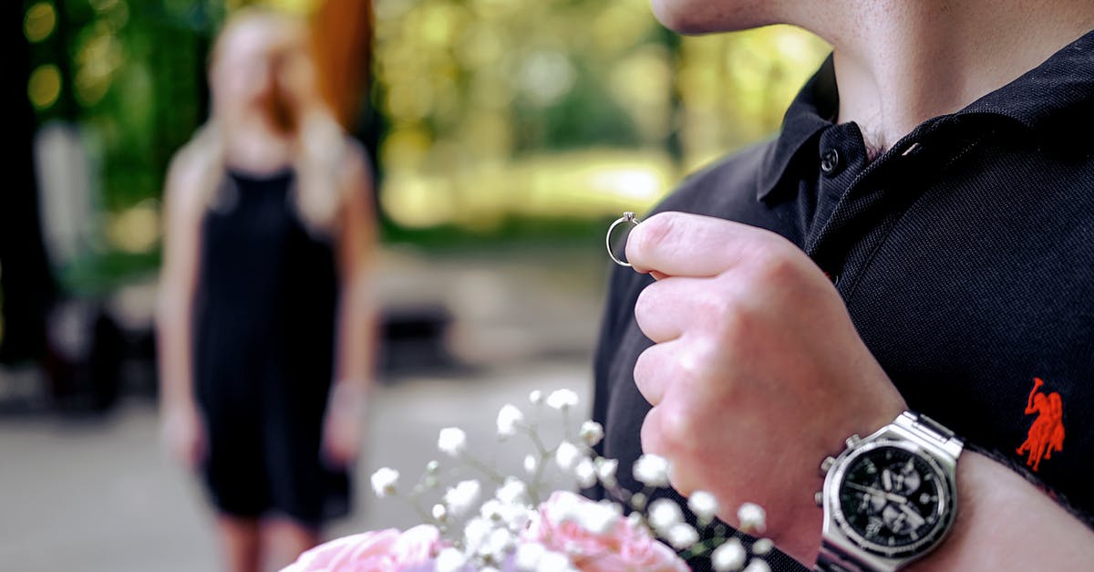 Why did Bradford give Chen a ring? - Soft focus of young male in casual clothing holding wedding ring and bouquet of flowers while going to make proposal to woman in garden on blurred background