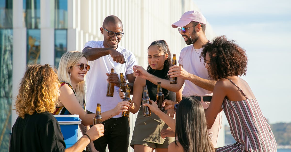 Why did Caleb try to get Nathan drunk the second time? - Group of cheerful multiracial friends in casual summer outfits toasting with beer bottles while having party on rooftop in urban environment