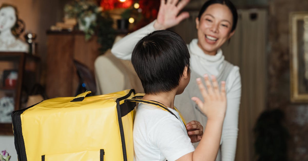 Why did employees get fired before the big recession? - Happy ethnic female cafe worker in apron wishing farewell to boy with food delivery backpack helping in family business