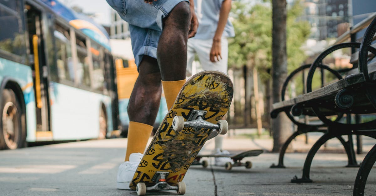 Why did Friends stop being produced - Crop unrecognizable male in yellow socks standing on colorful skateboard tail and deck at angle with friend while waiting for bus on bus stop