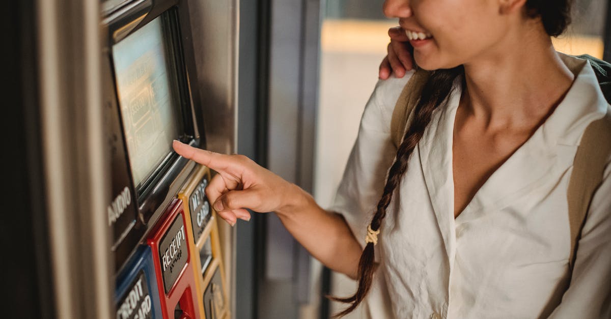 Why did Harold, John, and Root continue to use the subway tunnel after Shaw was captured? - Crop smiling Asian female in white shirt using ticket vending machine with touch screen in underground