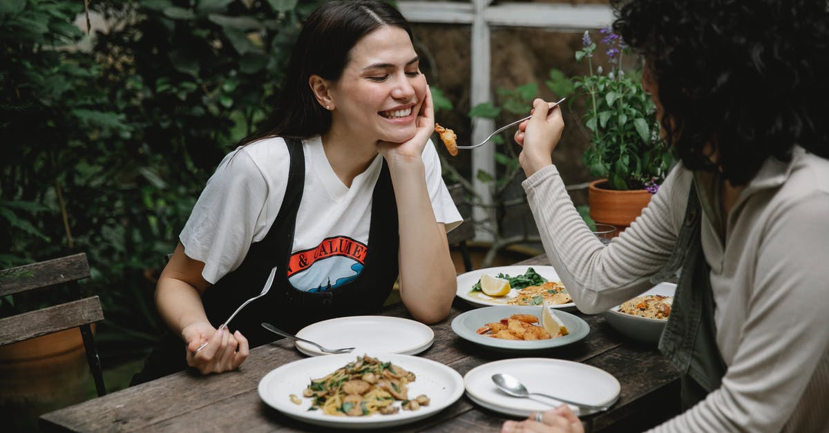 Why did Joy give Sadness the core memories? - Female giving food on fork to cheerful friend while having lunch in outdoor terrace
