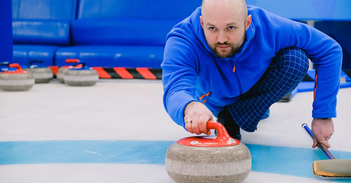 Why did Ken steal and then throw away batteries (end of S2E2) - Concentrated sportsman in blue activewear squatting down and throwing heavy stone while playing curling on modern ice rink