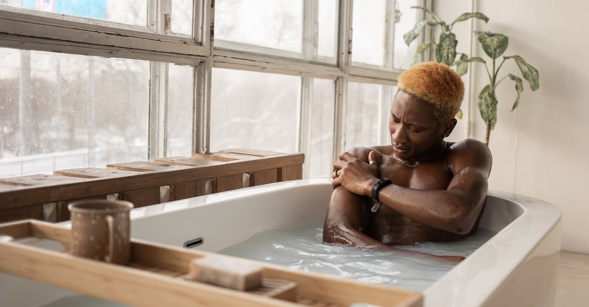 Why did Spider-Man take a detour to Dorset? - Young African American man with dyed hair and accessory sitting in bathtub full of water in light room with shabby window frames