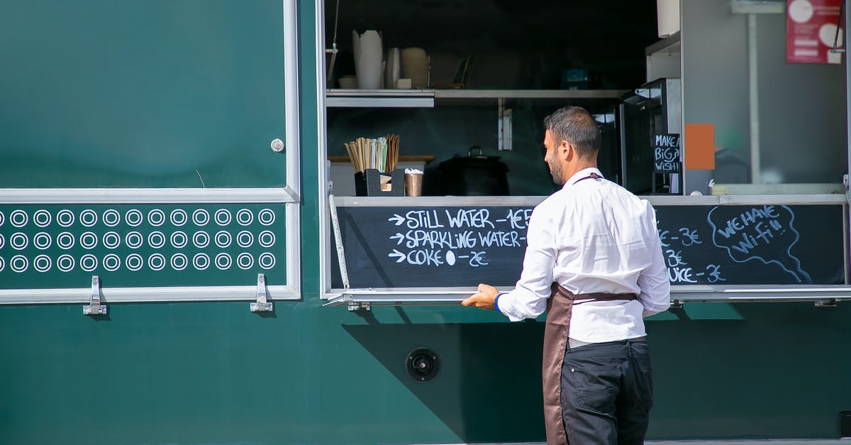 Why did Sulu go back to the job? - Back view of male seller wearing apron preparing food truck with menu written on board