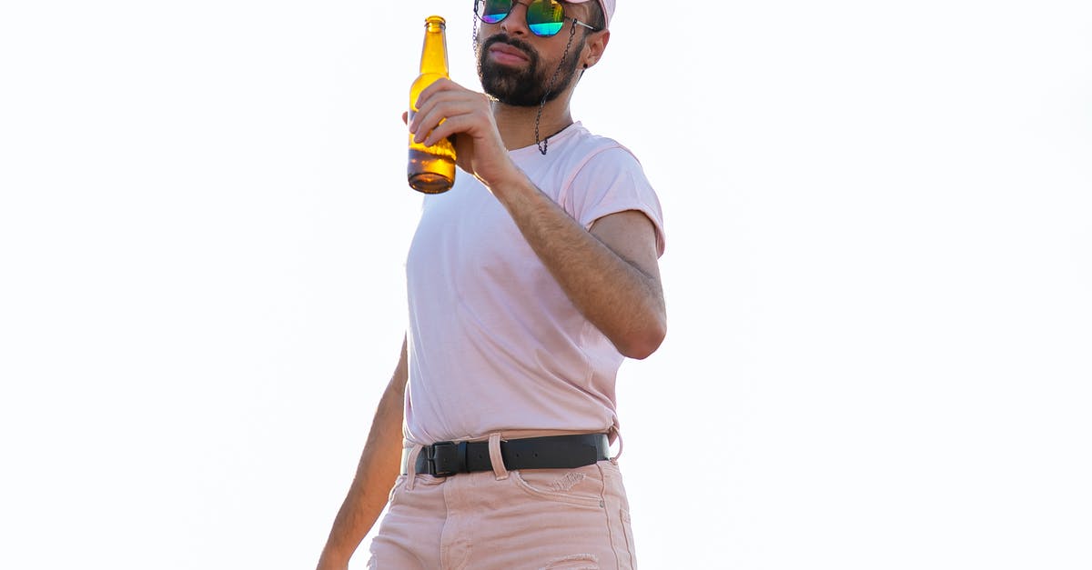 Why did Tallahassee shoot his alcohol bottle? - Masculine ethnic male in trendy wear and modern sunglasses holding bottle of alcoholic drink while looking at camera on white background