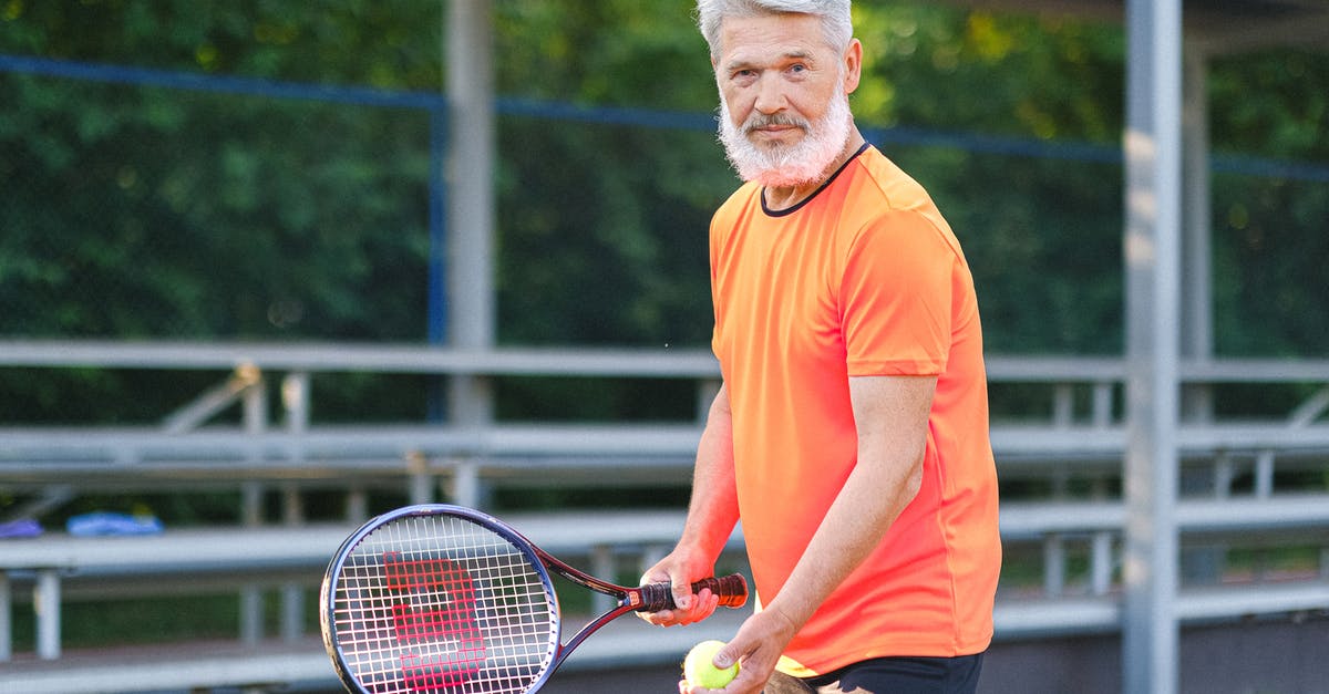 Why did the old man (player 001) vote as he did? - Positive senior sportsman in bright t shirt preparing to hit ball during tennis training on court in sunny day