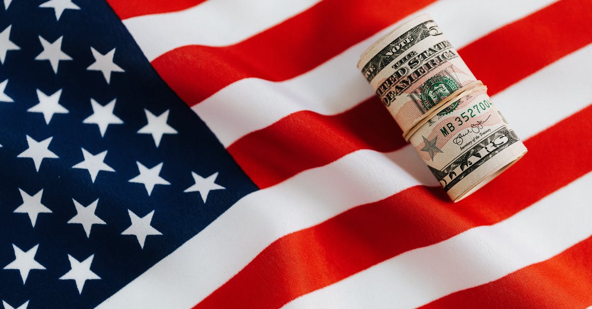 Why did the soldier slide 3 cartridges in the folded flag? - From above of United States currency folded in roll placed on USA flag illustrating concept of business profit and wealth