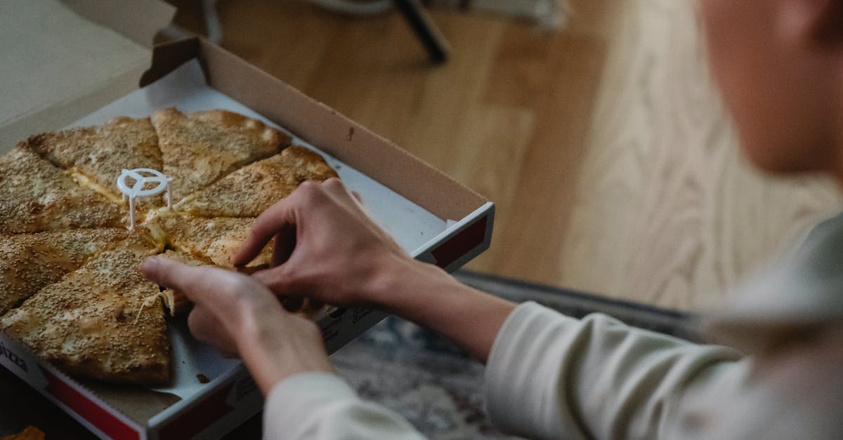 Why did the white people on Candieland respect or even take commands from Stephen? - From above crop anonymous person taking slice of delicious pizza from carton box on table spending evening at home