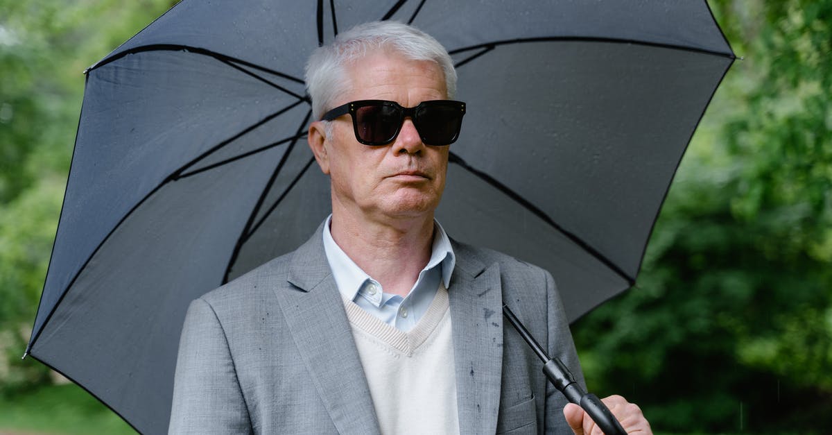 Why did Umbrella never use Nemesis to kill zombies? - Close-Up Shot of an Elderly Man in Gray Suit and with Sunglasses Using an Umbrella