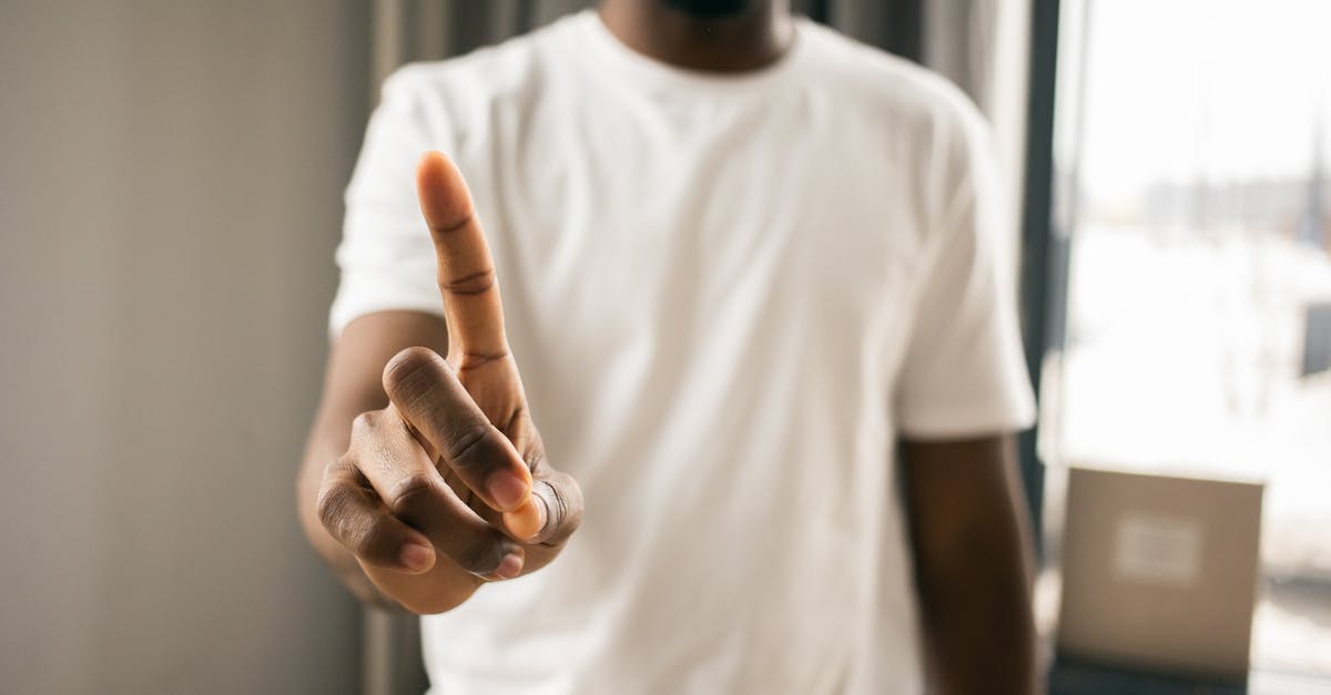 Why didn't the Celestials stop Thanos? - Crop anonymous African American male in white t shirt showing stop gesture with index finger pointing up in light room on blurred background