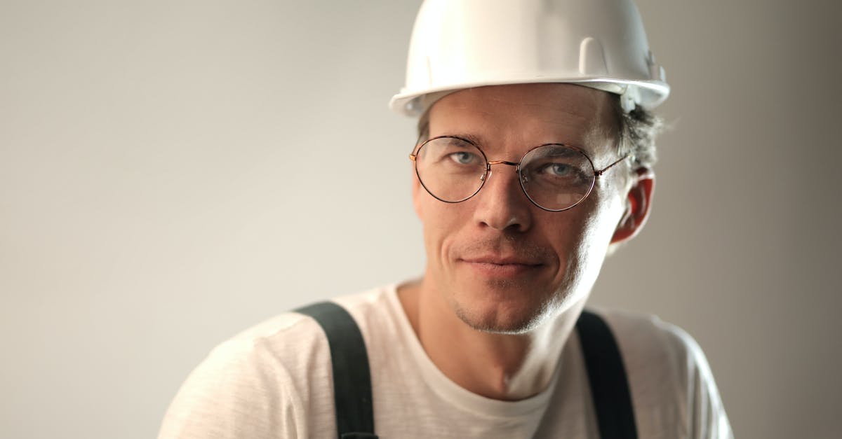 Why didn't the Vulcan nerve pinch work? - Content male builder in workwear and hardhat smiling on gray background in studio and looking at camera