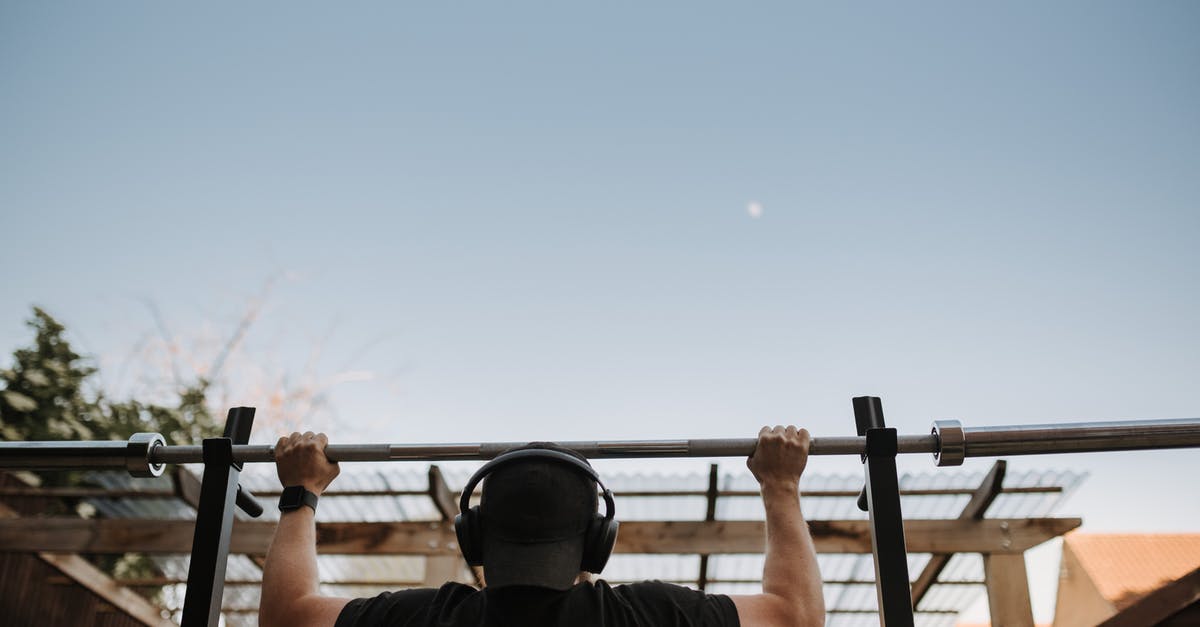 Why didn't Wilford use the back of the train just as a breeding camp? - Back view of anonymous muscular male athlete listening to music in headphones while exercising on bar under light sky