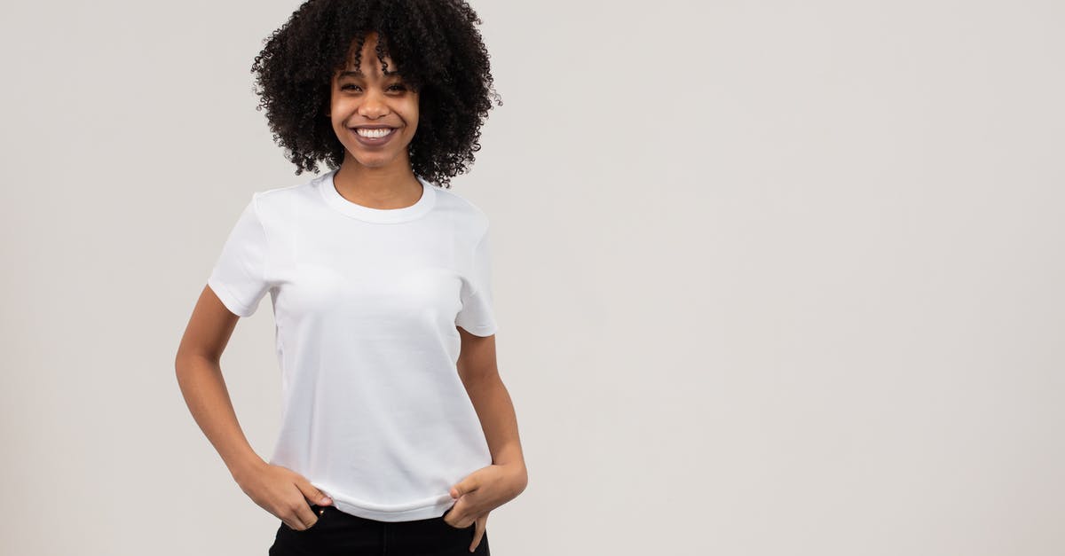 Why didn't young Barry disappear? - Positive young black female millennial with dark Afro hair in white t shirt smiling and looking at camera while standing in light studio with hands in pockets