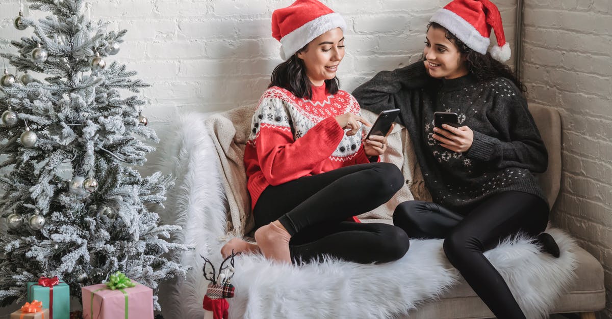 Why do Adam and Eve live so far apart? - Cheerful women using smartphones while celebrating Christmas holiday at home