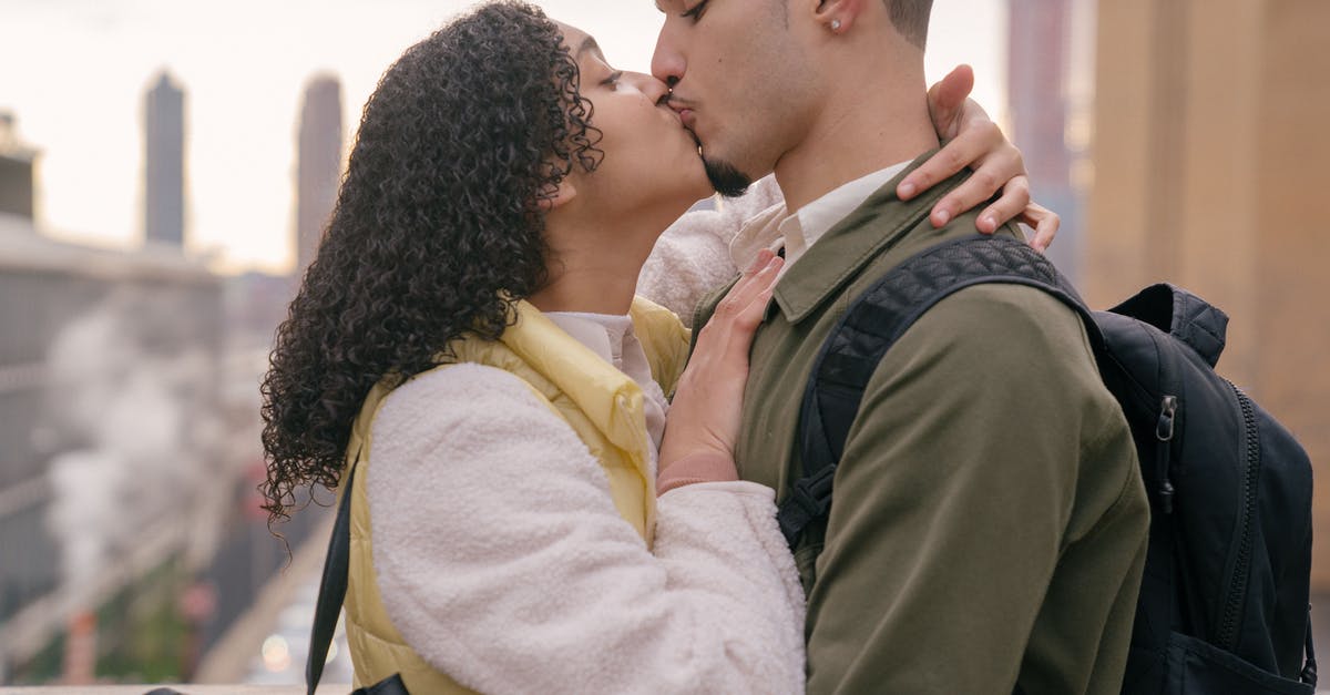 Why do Dan and Sandy kiss each other? - Side view of crop ethnic boyfriend kissing young girlfriend on blurred background of town