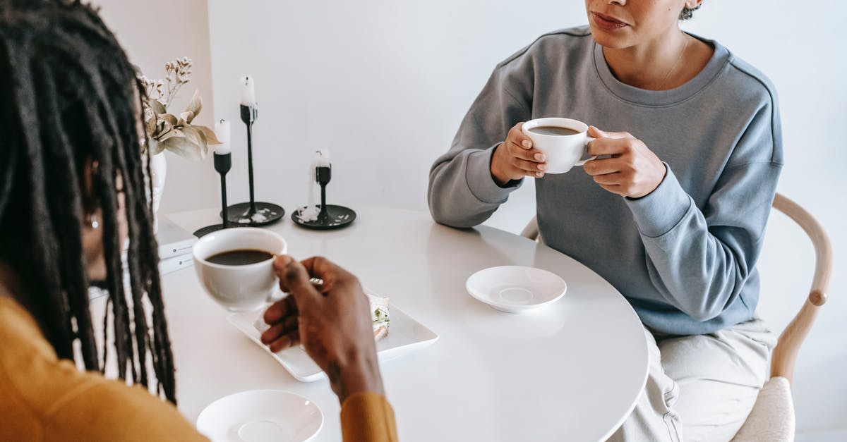 Why do Ethan and Julia just prefer to see each other from long distance rather than meeting each other? - From above of crop pensive Hispanic female in casual clothes sitting at light table and drinking coffee with African American boyfriend in modern cafe