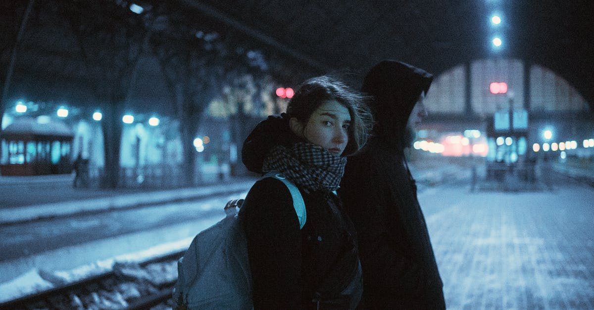 Why do Mickey's ears rotate and shift location when he is not facing the camera? - Young female in warm clothes standing near male in hood standing near railroad at nign in winter time and looking at camera