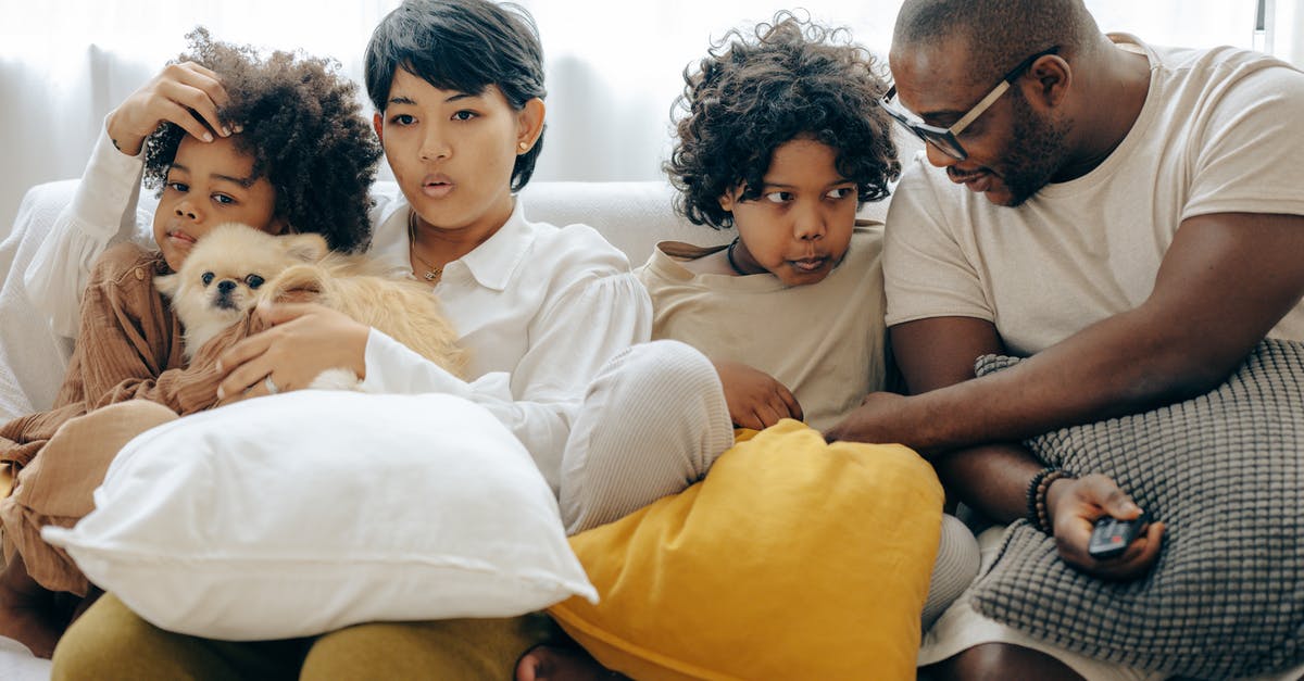 Why do Ray Barone's parents come in the back door half the time? - Multiracial family resting on comfortable sofa together with little dog while mother and little son watching TV with interest and father and elderly son talking to each other