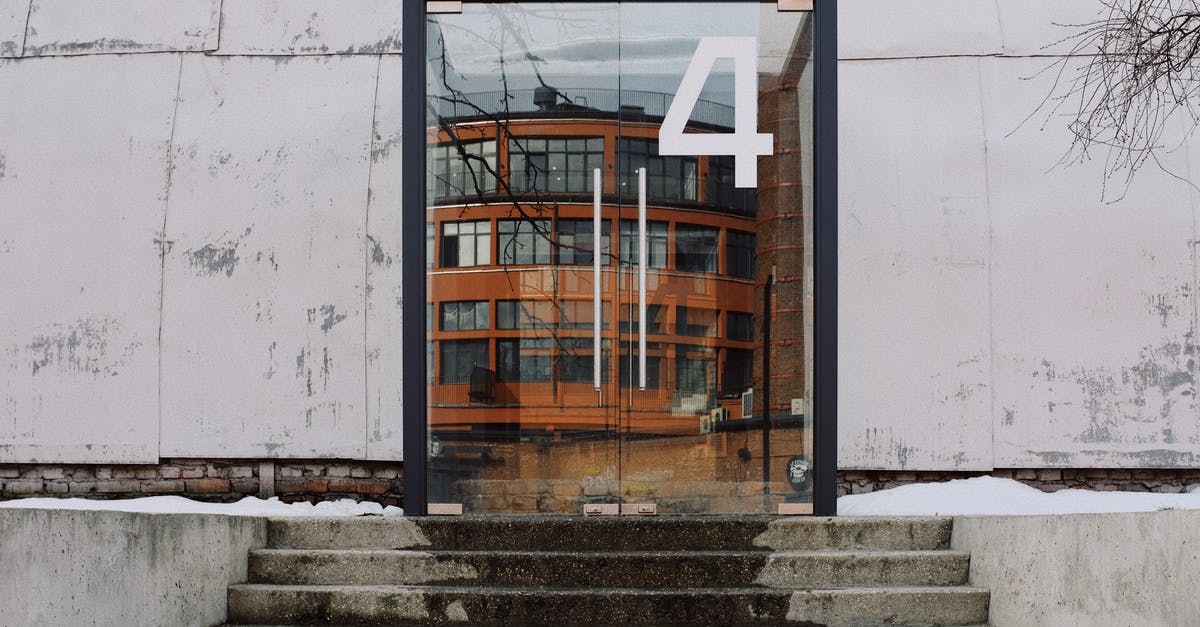 Why do so many TV shows have a step down from the front door into the living room? - From below of modern building facade with number four on glass entrance door and stairs