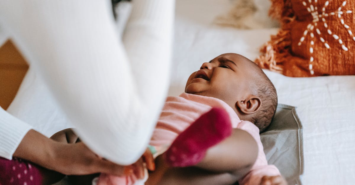 Why do the children not cry when they are taken from their homes? - From above of crop anonymous mom soothing sweet small African American girl on bed