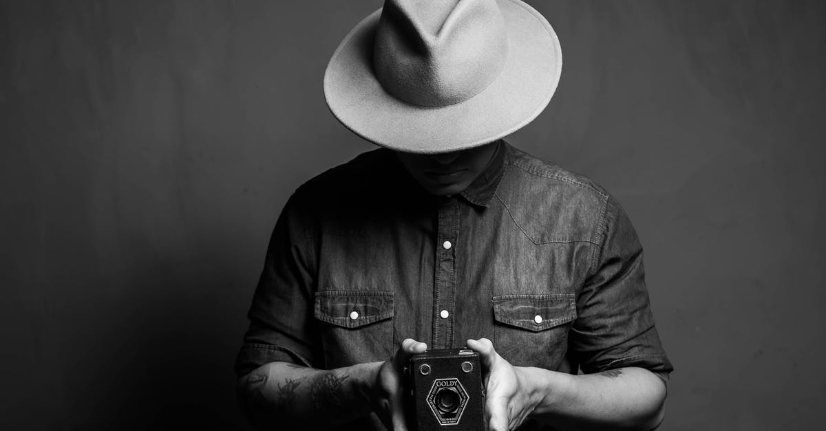 Why do they also carry other guys' photos if they know Mitch Leary is the assassin? - Man in hat showing retro camera