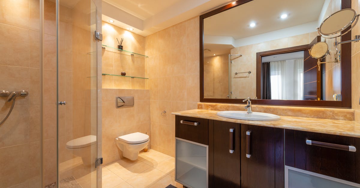 Why do they go to the toilet and put the hose in it to breathe? - Shower room against toilet bowl and cabinet with washbasin under mirrors illuminated by shiny lamps in modern house