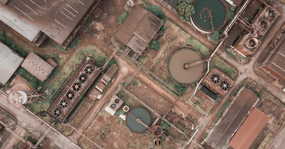 Why do they sometimes not use a real operating system in films? - Drone view of shabby factory with round settling tanks with mechanical means removing solids in water treatment plant