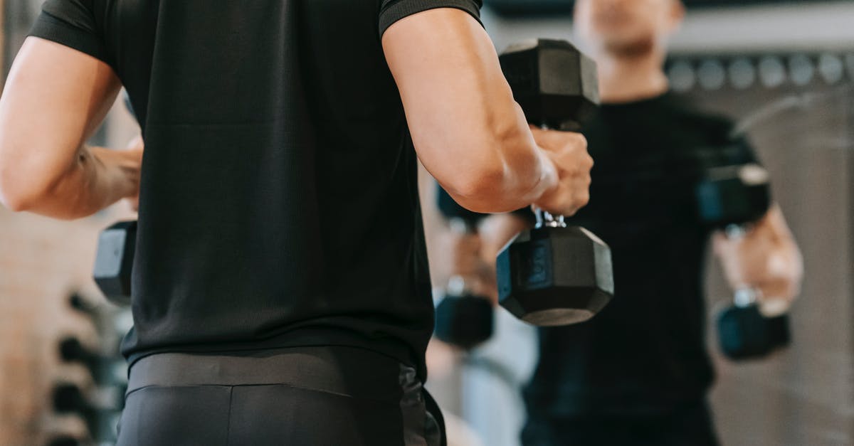 Why do tough guys chew toothpicks or match-sticks? - Crop sportsman with dumbbells in fitness studio