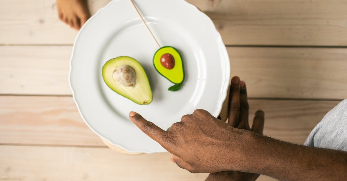 Why do translated subtitles differ from the dubbed voice? - Top view of crop anonymous African American man pointing on organic healthy avocado helping child to choose between natural fruit and sweet lollipop