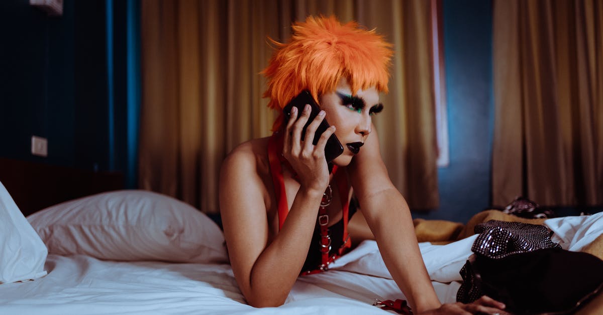 Why does a character talk to the back of another character? - Seductive young ethnic female with makeup in orange wig lying on bed and chatting on mobile phone