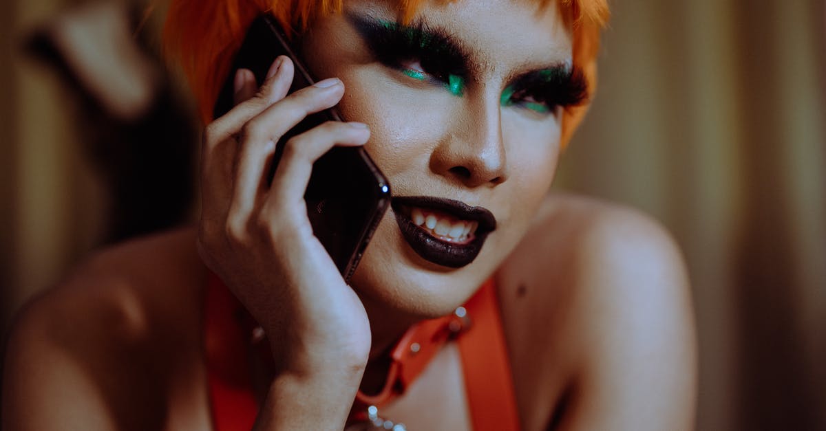 Why does a character talk to the back of another character? - Crop young informal ethnic lady with bright makeup and short orange hair smiling while lying on stomach and talking on smartphone