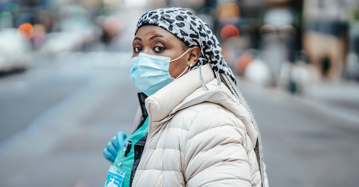 Why does Aaron Cross lie about being out of medication? - Side view thoughtful African American nurse wearing protective respirator and gloves crossing road in modern city and looking at camera