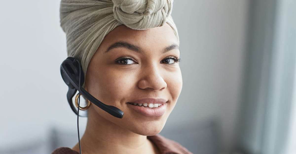 Why does Agent Smith call the Oracle mom? - Delighted African American female call agent with headset wearing turban looking away while standing in light room on blurred background
