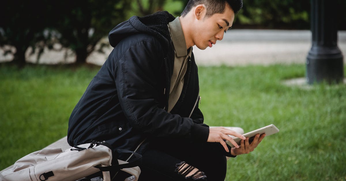 Why does Dakuan use this specific poison in Ninja Scroll? - Side view of focused young Asian male student in casual clothes sitting on bench in park with backpack and browsing internet on tablet