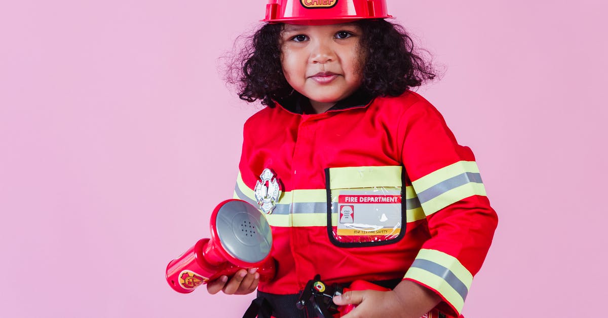 Why does fake blood in older movies look so fake? - Little ethnic child wearing fireman costume with fire extinguisher and loudspeaker toy with hardhat and standing on pink background and looking at camera