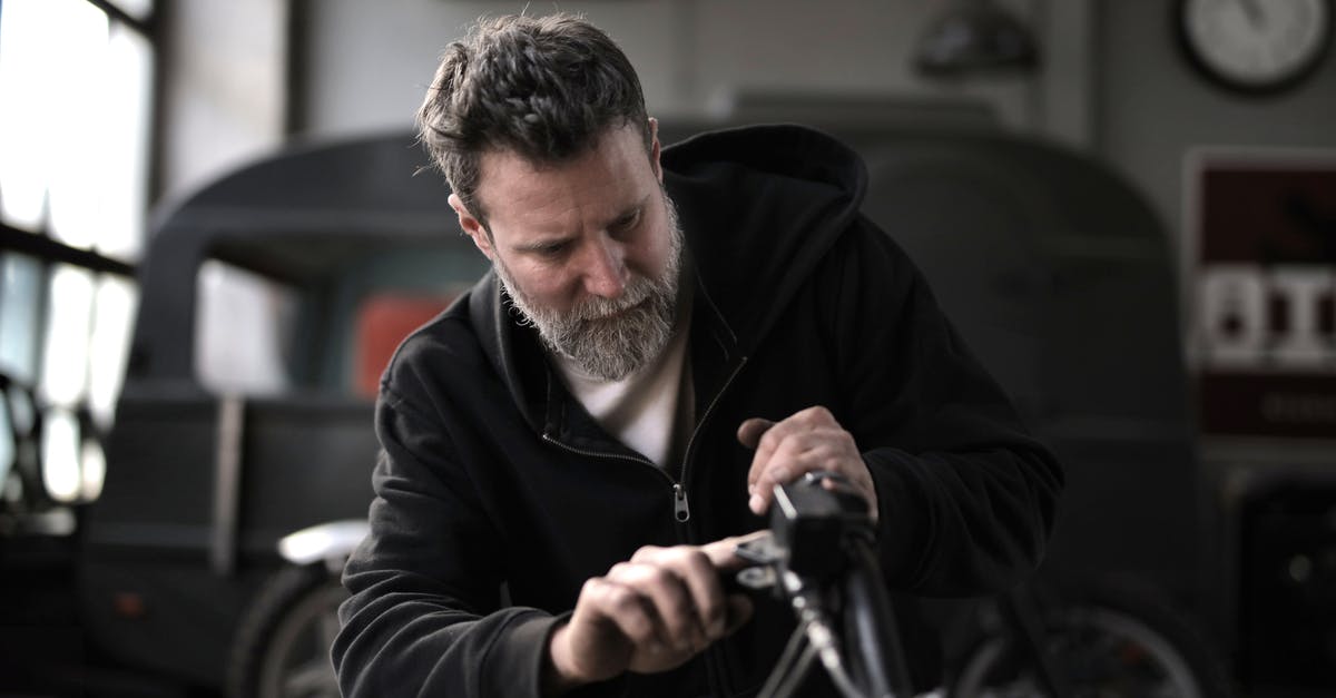 Why does George Mcfly employ Biff to wax his car after he had previously tried to rape his wife? - Concentrated male biker in casual wear fixing motorcycle part while working in garage