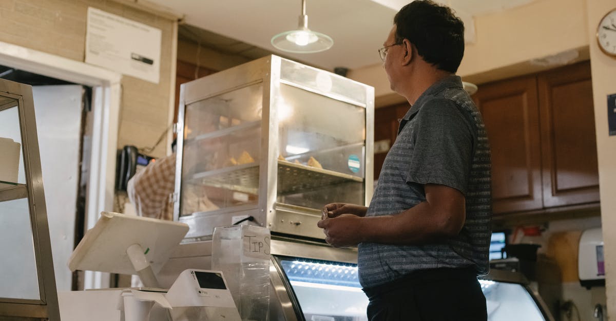 Why does Harold choose to lock down the machine again? - Side view of ethnic male wearing casual clothes standing near showcase and cash register while buying food in grocery store