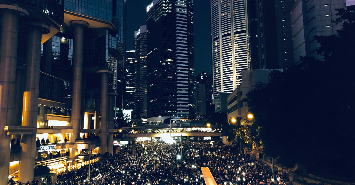 Why does Holden have a panic attack after meeting with Kemper? - From above of crowd of people standing on street in dark modern city centre during mass protest