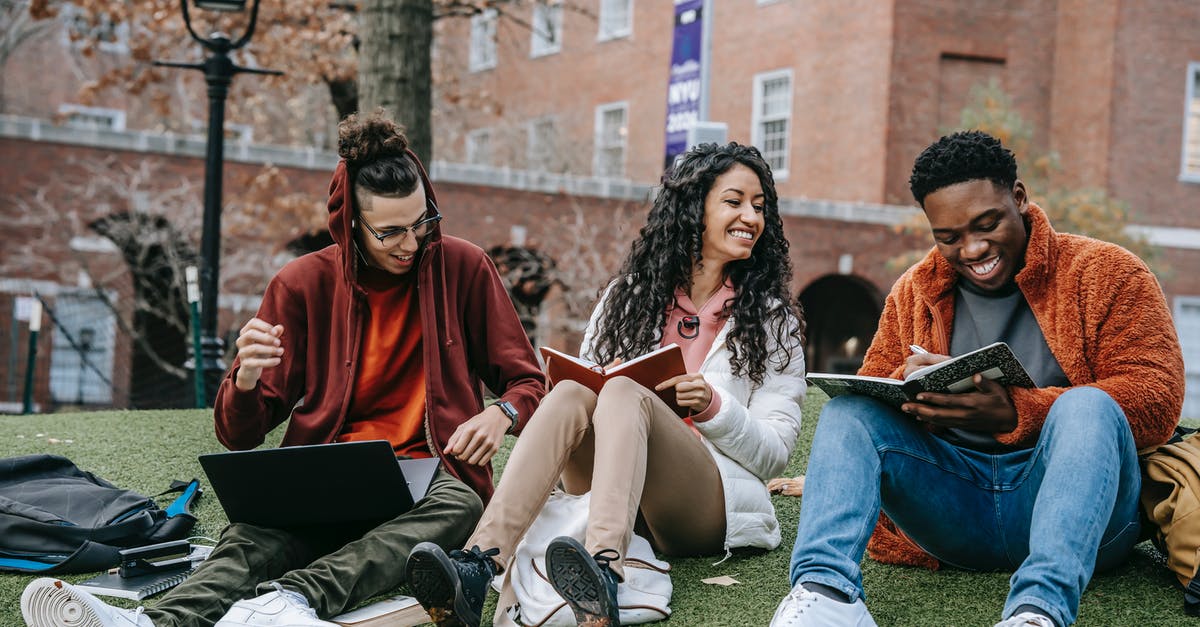 Why does Indy pause while writing "neolithic" in the campus scene? - Full body of happy diverse students with notebooks and laptop sitting on grassy lawn on campus of university while studying together