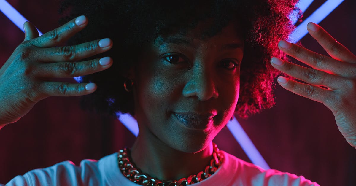 Why does Joy glow? - Cheerful black woman raising hands near face in neon illumination