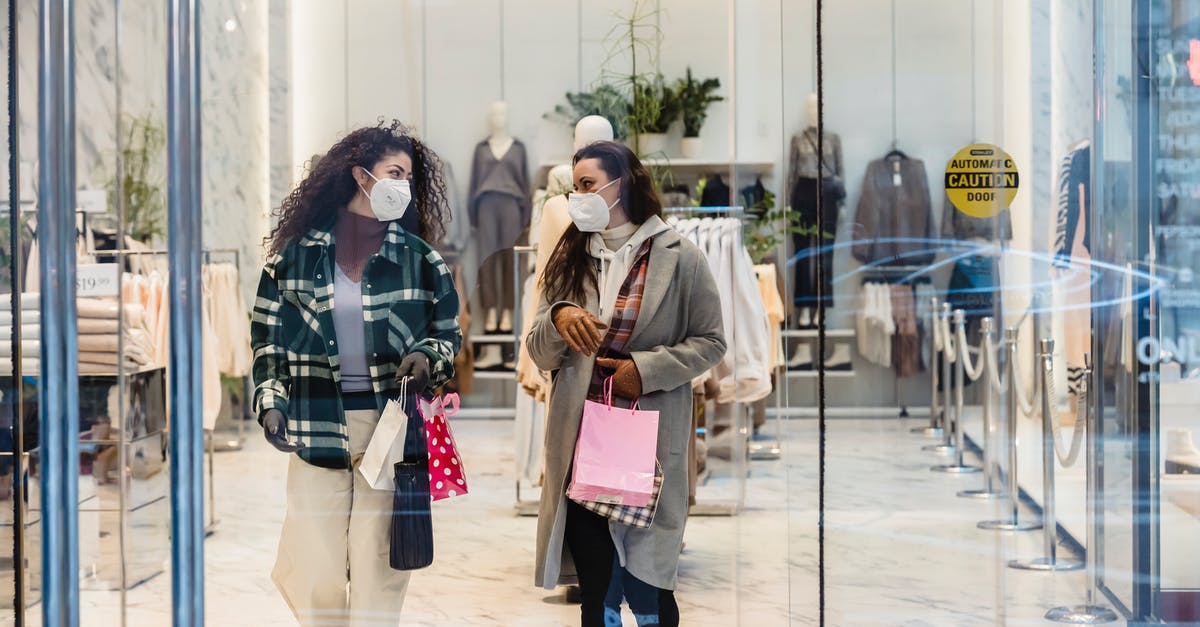 Why does Karen speak three different languages? - Through glass of female friends in protective masks carrying shopping bags while walking out of clothing store