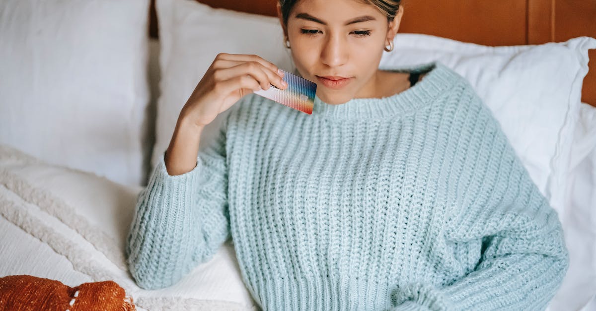 Why does King Schultz go to such distance in order to help Django? - Crop concentrated Asian female in knitted blue sweater lying on cozy bed with credit card