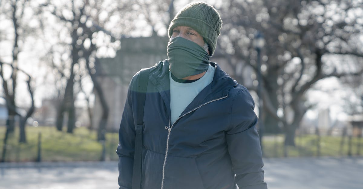 Why does Lefty's gang have to stand outside in cold weather like this? - Male in warm clothes standing on street with face covered by scarf on blurred background of leafless trees