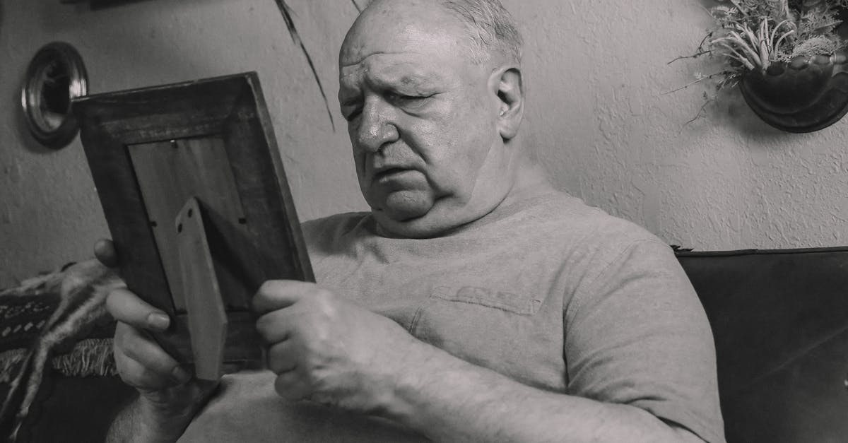 Why does Lucy cry in pain after seeing the old man beside her? - A Grayscale Photo of an Elderly Man Holding a Wooden Frame