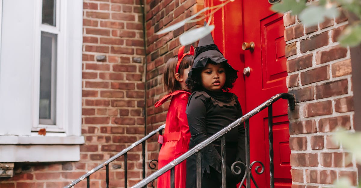 Why does Mary Poppins not acknowledge the fantasy adventures she takes the children on? - Multiethnic kids dressed for Halloween celebrations standing near front door of red brick house playing trick or treat custom