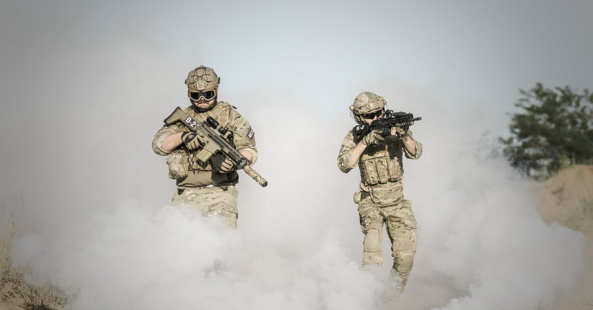 Why does Mikey attack the INS Agent? - Men Holding Rifle While Walking Through Smoke Grenade