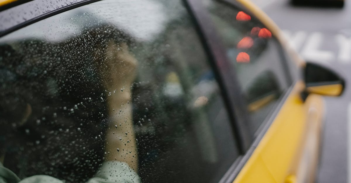 Why does Milton Arbogast exit his car by sliding across to the passenger side and getting out through the right hand door? - Crop anonymous passenger sitting in yellow taxi car on road in town in rainy weather