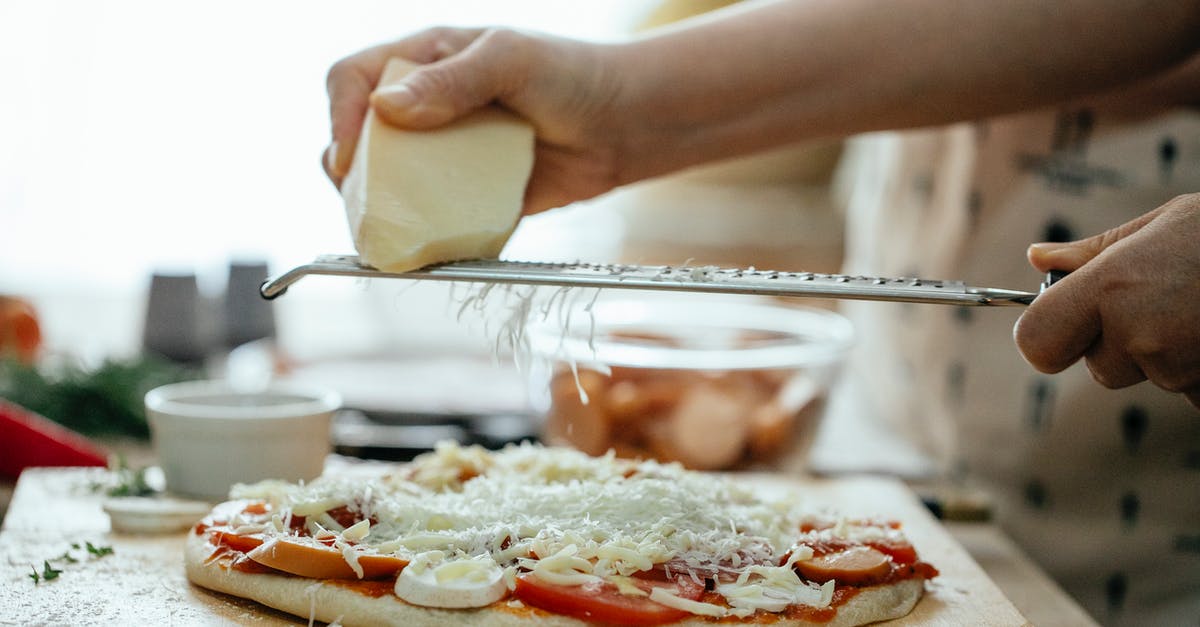 Why does Orochimaru put cursed seals on people? - Side view of crop unrecognizable person grating piece of hard cheese on palatable homemade pizza in kitchen at daytime